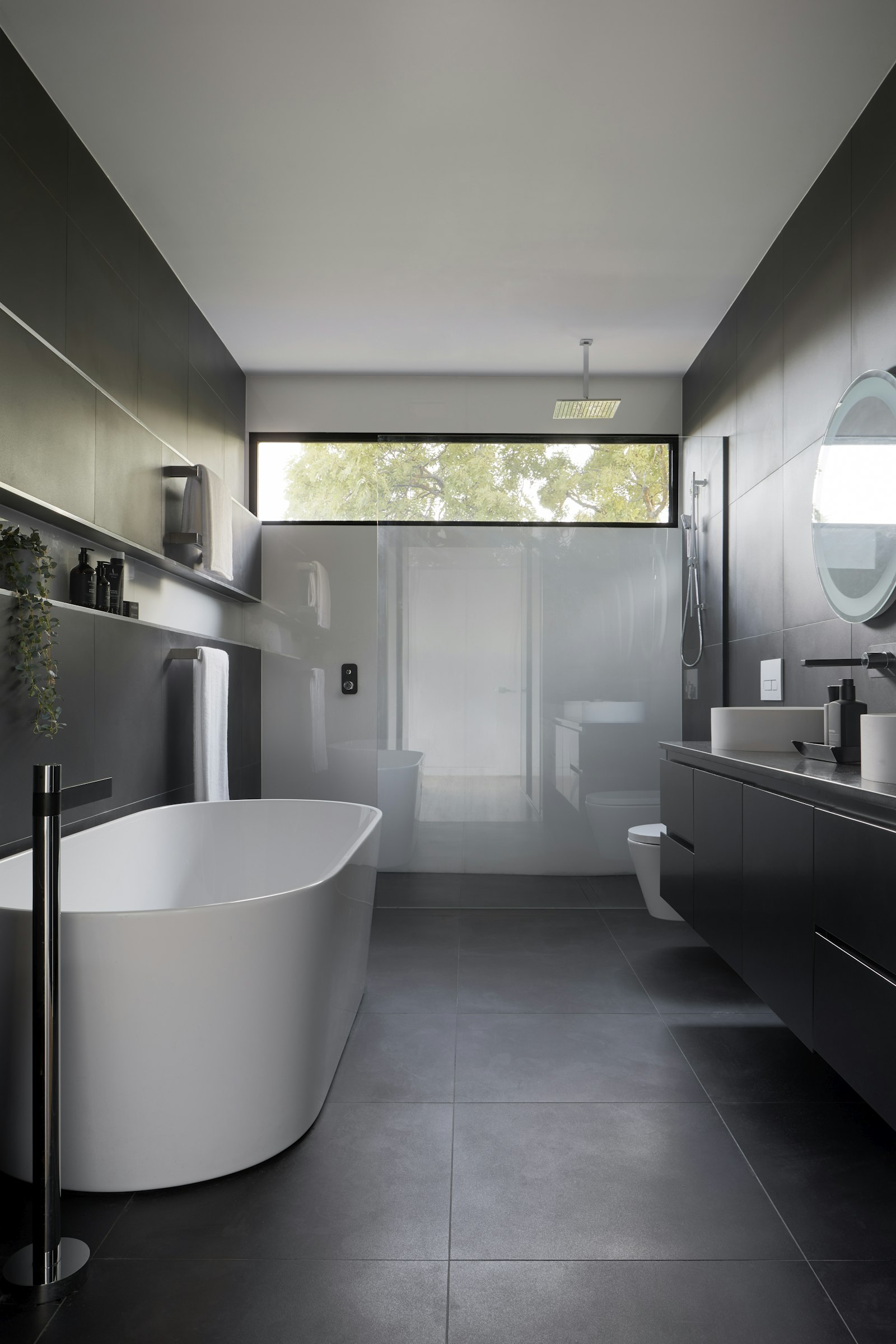 Freestanding soaking tub beneath a window in a remodeled Long Island bathroom